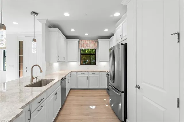 a kitchen with granite countertop a refrigerator a stove a sink and chairs