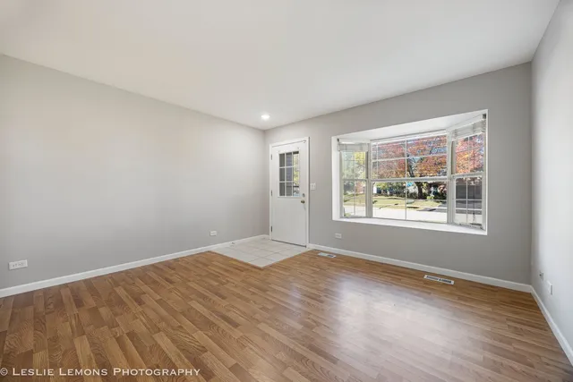 a view of an empty room with a window and wooden floor