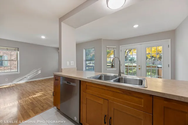 a living room with stainless steel appliances granite countertop a sink and dishwasher with wooden floor