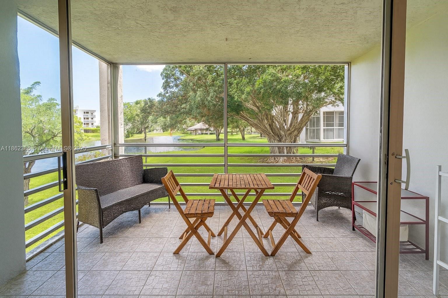 9330 Lagoon Place, Unit 206 Davie, FL 33324 - Photo 14 of 17 a view of chairs and table in patio with a yard