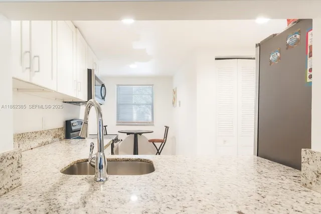 a view of kitchen with granite countertop sink and a refrigerator