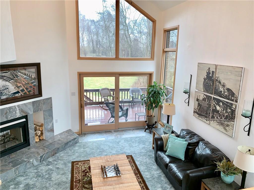 3450 Pinewood Road Irwin, PA 15642 - Photo 11 of 25 Main level living room featuring a propane burning fireplace with beautiful ceramic surround and sliders to deck