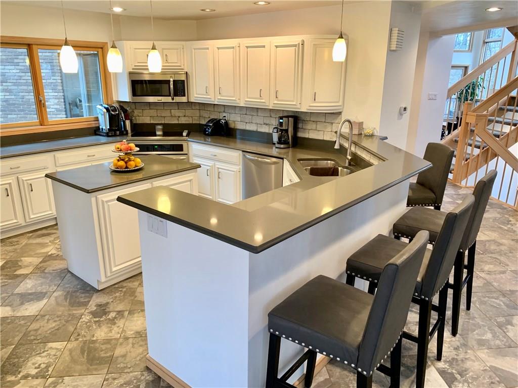 3450 Pinewood Road Irwin, PA 15642 - Photo 4 of 25 white and bright~ this stunning open kitchen features tons of cabinets, beautiful quartz counter tops with plenty of roof for food prep, high end stainless appliances, and wine cabinet.
