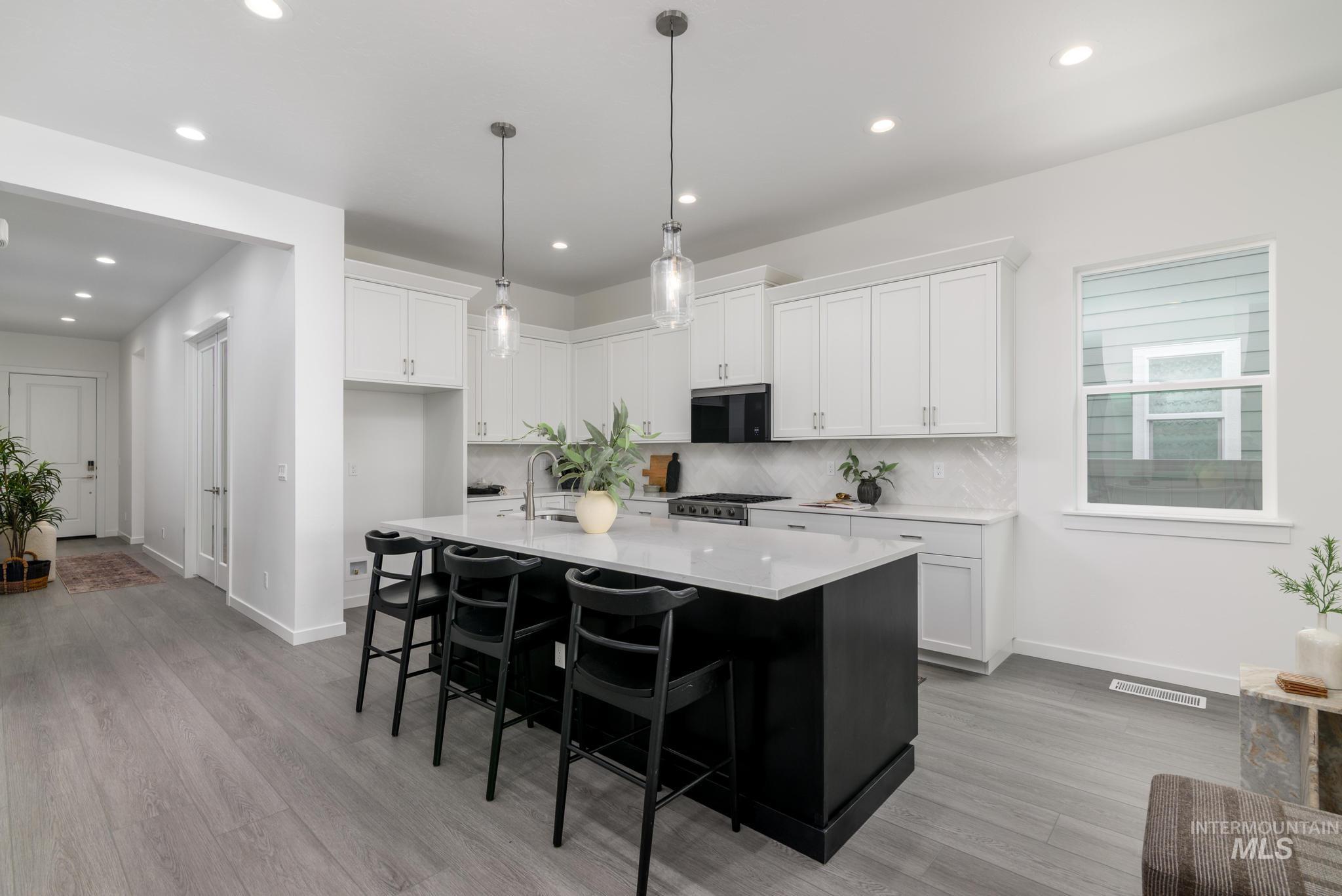 8554 West Fanning Street Star, ID 83669 - Photo 5 of 11 Kitchen with dark cabinets, white cabinetry, a center island with sink, a kitchen breakfast bar, and hanging light fixtures