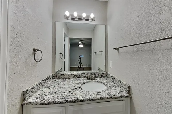 a bathroom with a granite countertop sink and a mirror