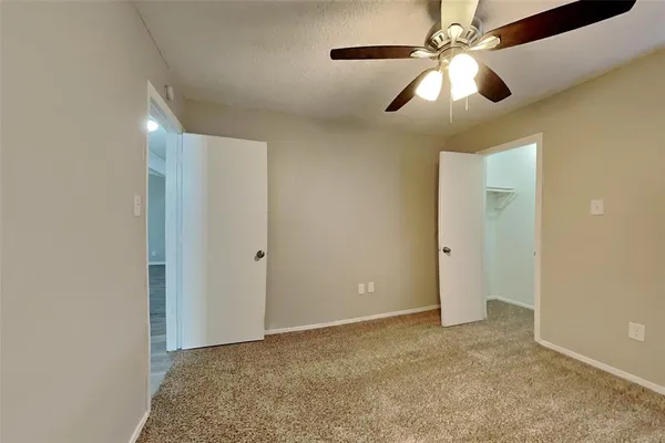 an empty room with closet and a chandelier fan