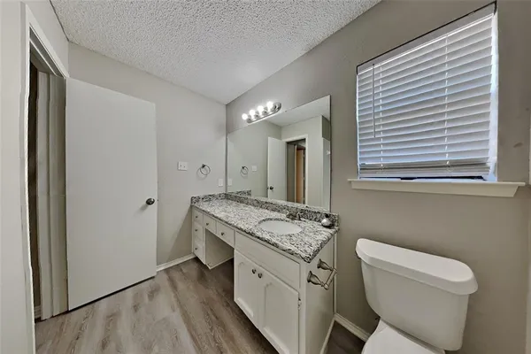 a bathroom with a granite countertop toilet a sink and a mirror