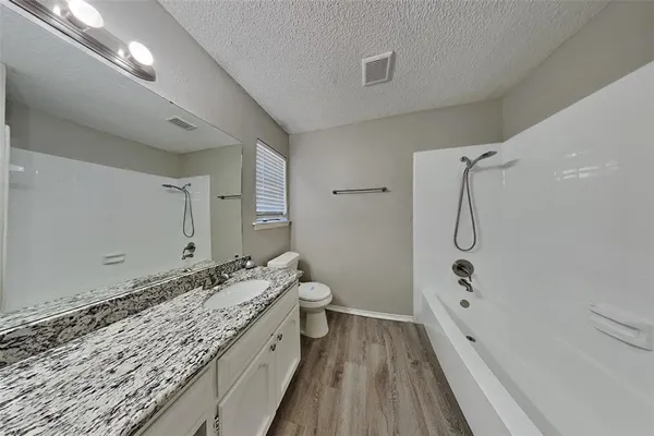 a bathroom with a granite countertop sink a toilet and shower