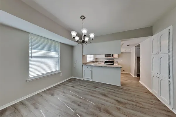 a kitchen with stainless steel appliances kitchen island granite countertop a refrigerator a sink dishwasher a stove and white cabinets with wooden floor