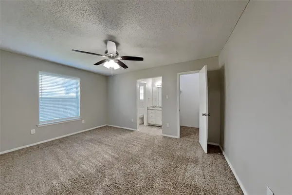 an empty room with chandelier fan and windows