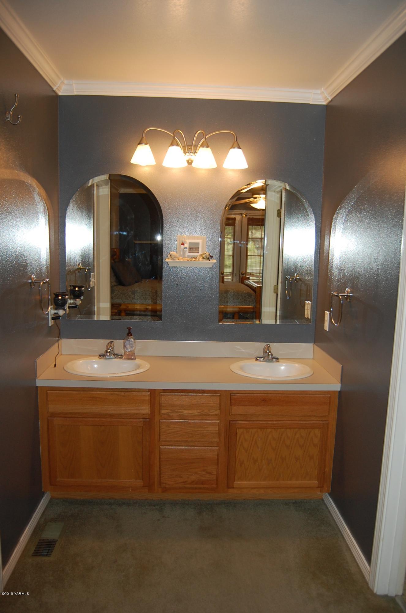 15021 Douglas Road Yakima, WA 98908 - Photo 15 of 35 a bathroom with double vanity sinks a large mirror and a lamp