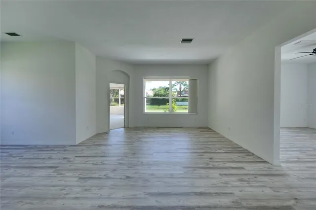 a view of kitchen and empty room with wooden floor