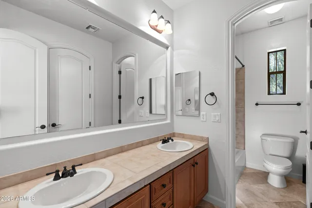 a bathroom with a granite countertop sink a toilet and a mirror