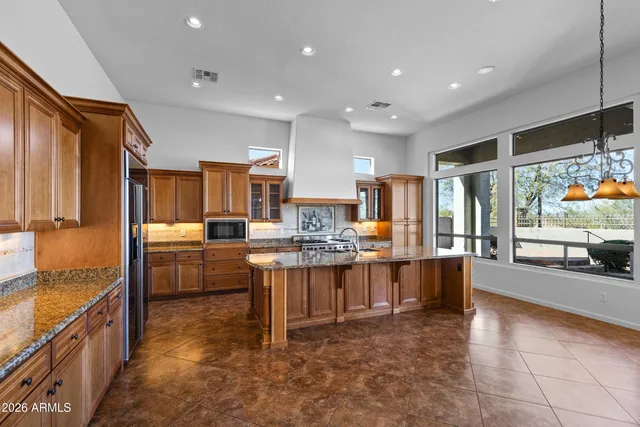 a large kitchen with kitchen island a large counter top space a sink stainless steel appliances and cabinets