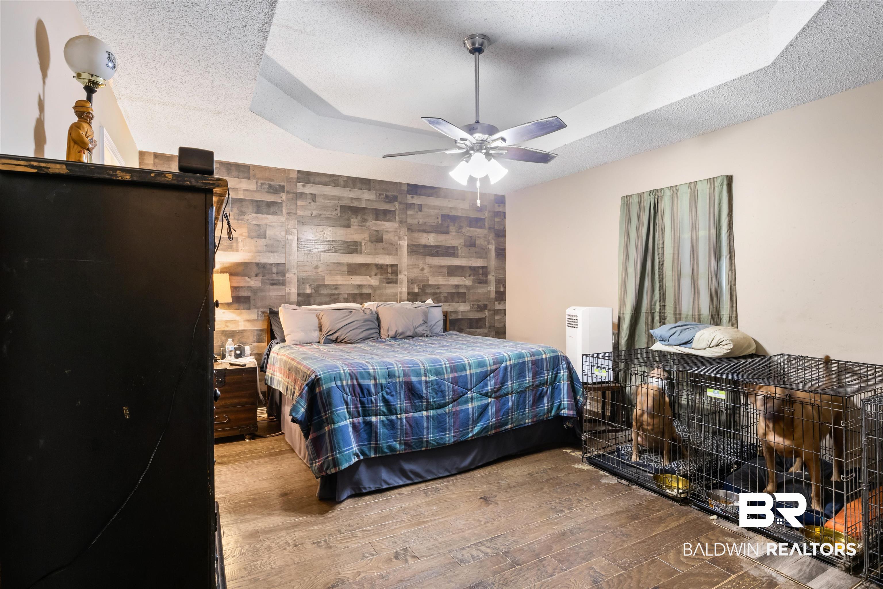 1345 Baker Court Mobile, AL 36695 - Photo 10 of 28 Bedroom featuring a tray ceiling, light hardwood / wood-style flooring, tile walls, a textured ceiling, and ceiling fan