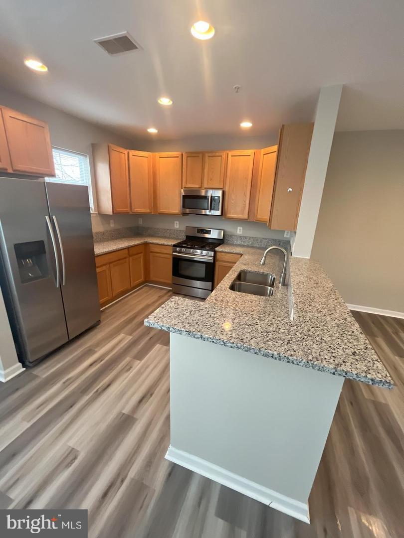 1321 Karen Boulevard, Unit 302 Capitol Heights, MD 20743 - Photo 3 of 14 a kitchen with granite countertop kitchen island stainless steel appliances a sink a stove a microwave a counter top and cabinets