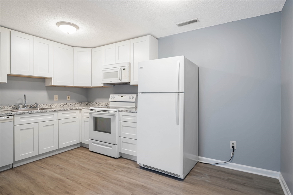 1475 Braley Road, Unit 22 New Bedford, MA 02745 - Photo 11 of 19 a kitchen with cabinets appliances wooden floor and a window