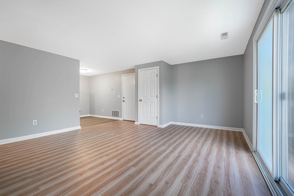 1475 Braley Road, Unit 22 New Bedford, MA 02745 - Photo 5 of 19 a view of an empty room with wooden floor and a window