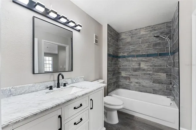 a bathroom with a granite countertop sink a toilet and bathtub