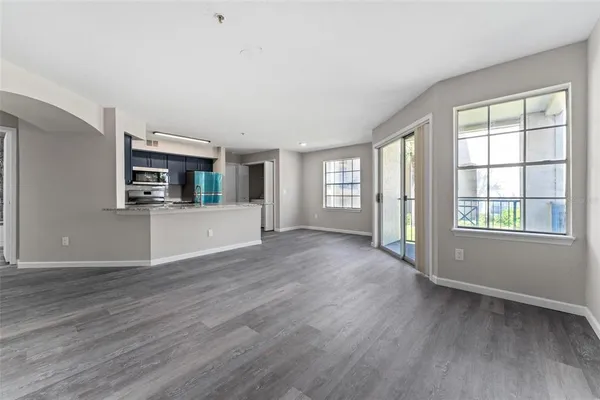 an empty room with wooden floor and a kitchen