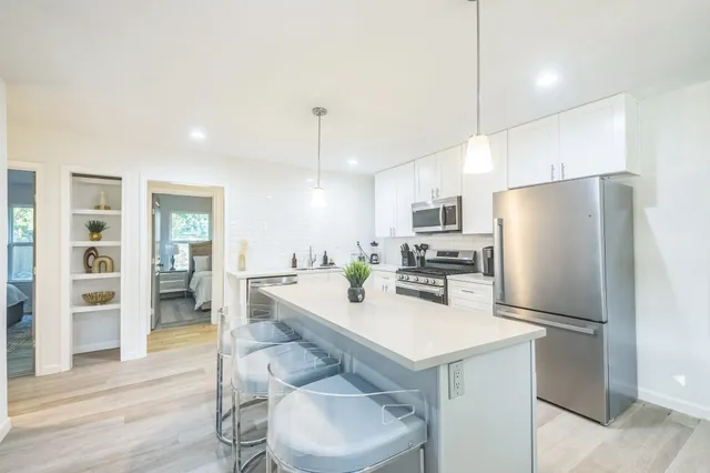 a kitchen with a sink a refrigerator and chairs
