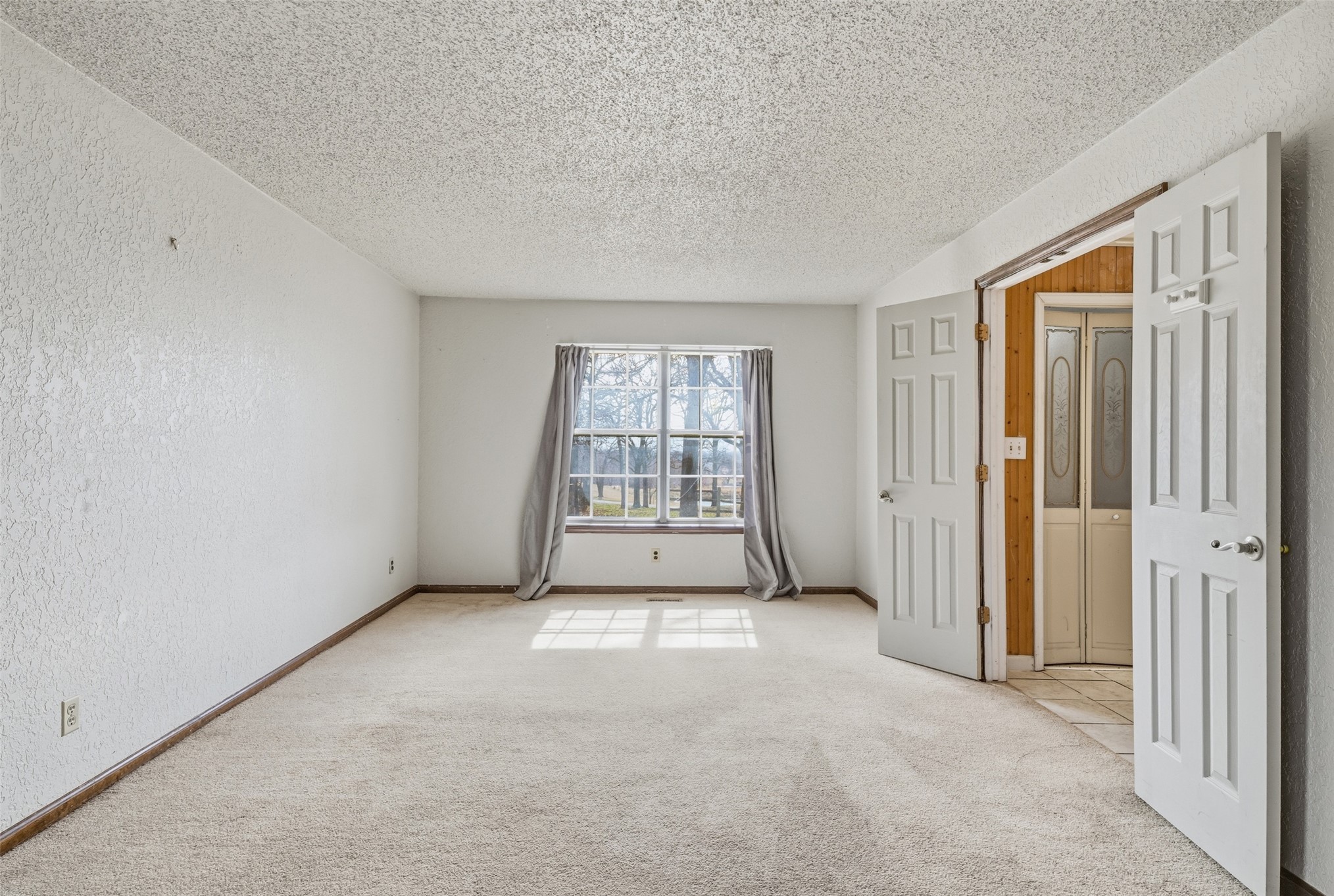 17875 East 589 Road Inola, OK 74036 - Photo 53 of 73 House #2 Expansive primary bedroom featuring light-toned carpeting, a textured ceiling, a large window, and double panel doors to bathroom and walk in closet.