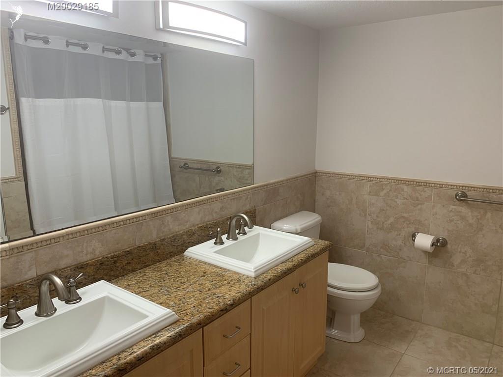 3129 Southeast Indian Street, Unit 3 Stuart, FL 34997 - Photo 8 of 10 a bathroom with a granite countertop sink a toilet and a mirror
