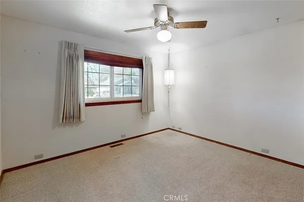 an empty room with windows and fan