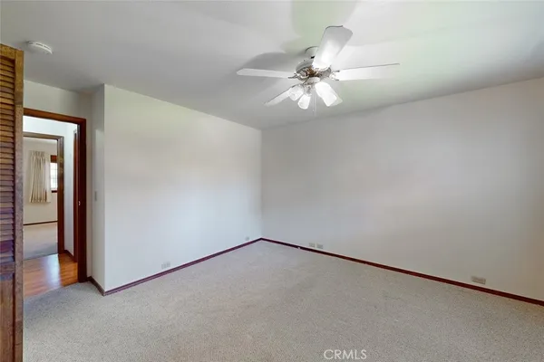 an empty room with windows and fan