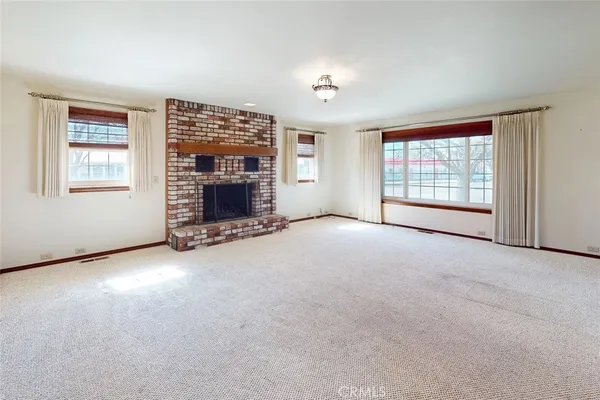 an empty room with windows and fireplace