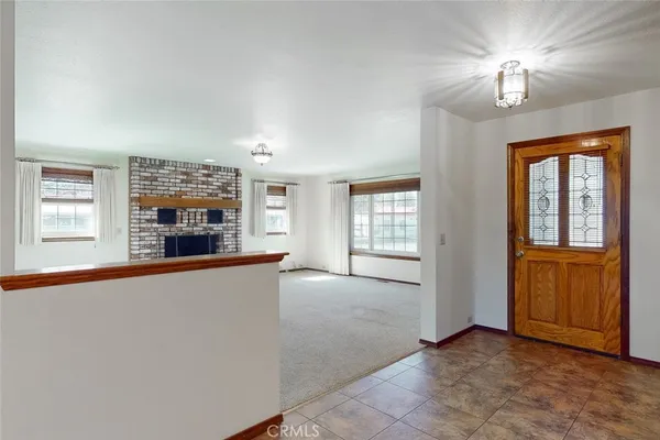 wooden floor in an empty room with a fireplace and a window