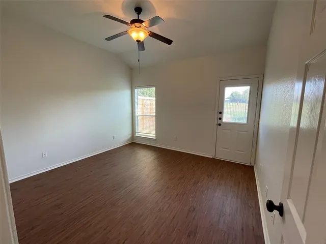 an empty room with wooden floor chandelier fan and windows