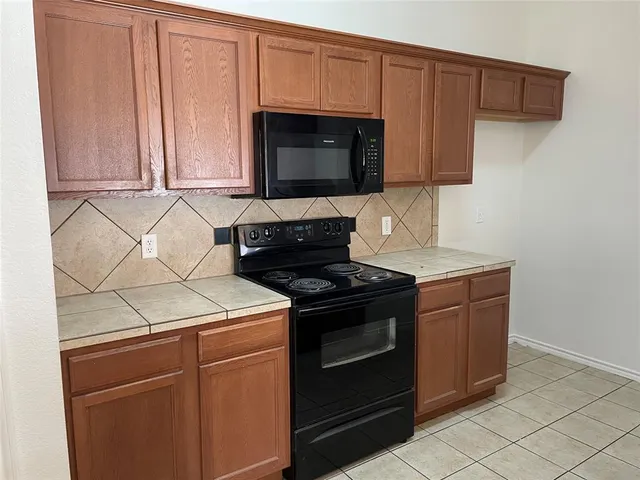 a kitchen with granite countertop white cabinets and stainless steel appliances