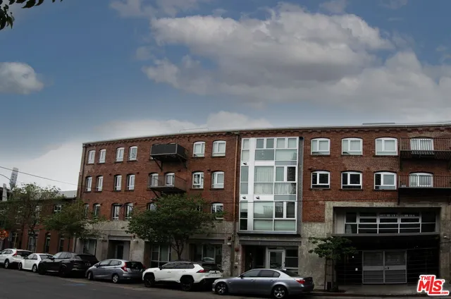 a front view of a building with lot of cars and trees