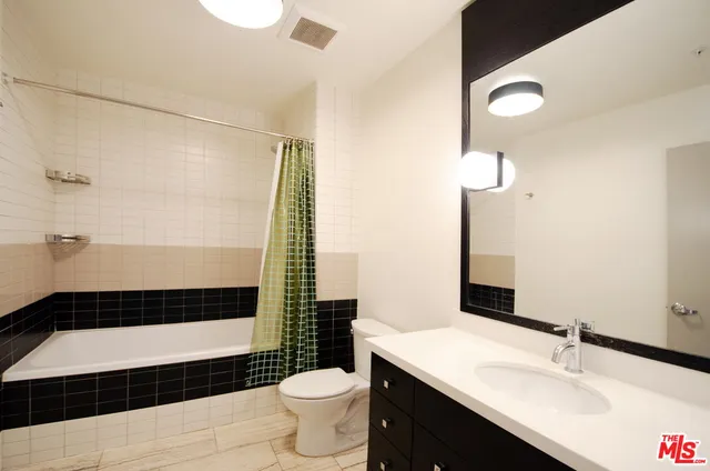 a bathroom with a sink a toilet a mirror and shower