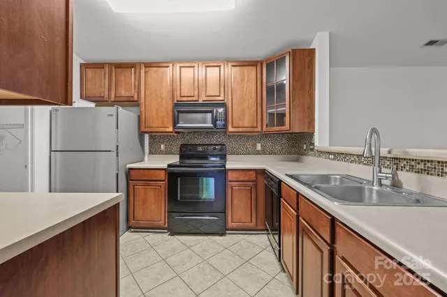 a kitchen with kitchen island granite countertop a refrigerator stove top oven and sink