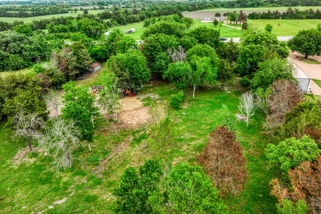 an aerial view of residential house with outdoor space and trees all around