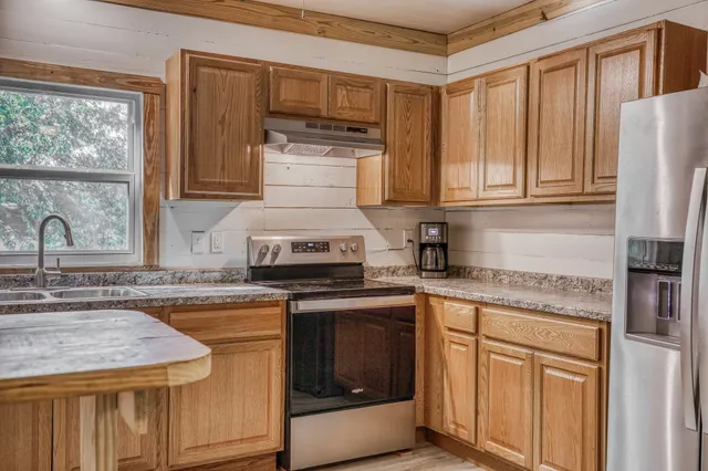 a kitchen with granite countertop a sink stove and refrigerator