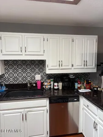 a kitchen with white cabinets and sink