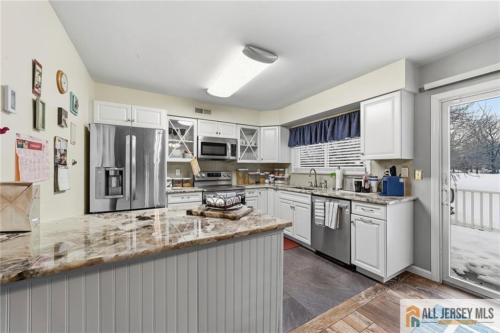 491A Delair Road, Unit 491B Monroe Township, NJ 08831 - Photo 6 of 22 a kitchen with stainless steel appliances granite countertop a stove top oven a sink dishwasher a refrigerator and white cabinets with wooden floor