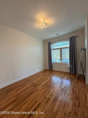 a view of an empty room with window and wooden floor