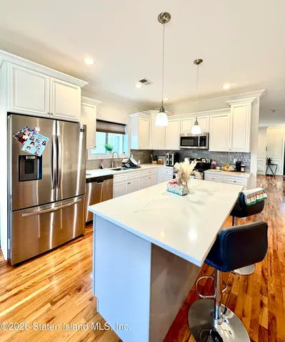 a kitchen with stainless steel appliances kitchen island granite countertop a table chairs refrigerator and microwave