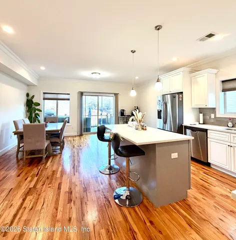a living room with a sink dining table wooden floor and a view of kitchen