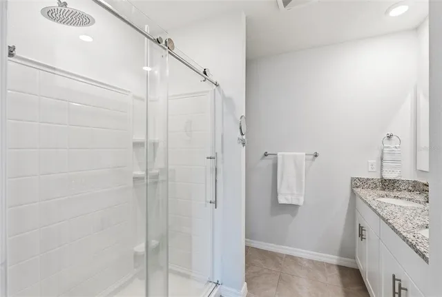 a bathroom with a granite countertop shower a sink and a mirror