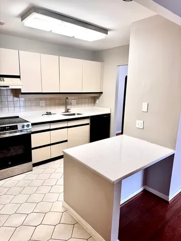 a kitchen with a sink a stove top oven and white cabinets