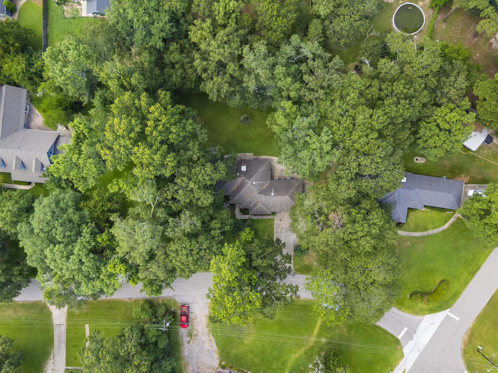 202 Sunset Boulevard Conroe, TX 77303 - Photo 45 of 50 This aerial photo shows a house surrounded by lush greenery, providing privacy and a natural setting. The property is nestled in a neighborhood with a few nearby homes, offering a spacious yard and a peaceful environment.