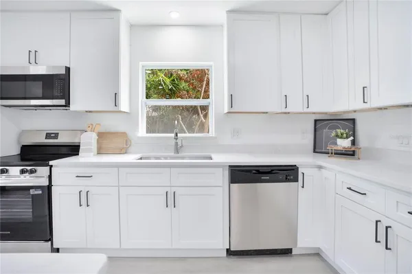 a kitchen with white cabinets and sink
