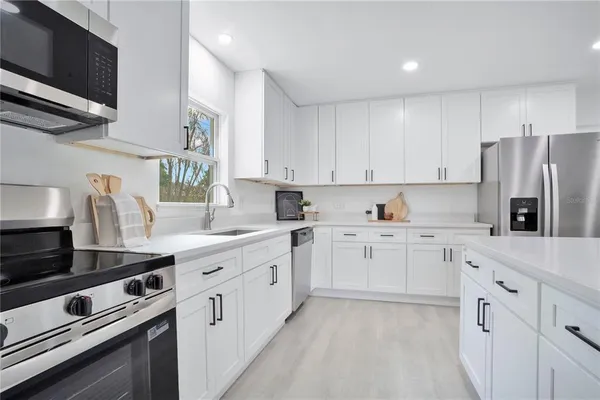 a kitchen with granite countertop white cabinets white stainless steel appliances and sink
