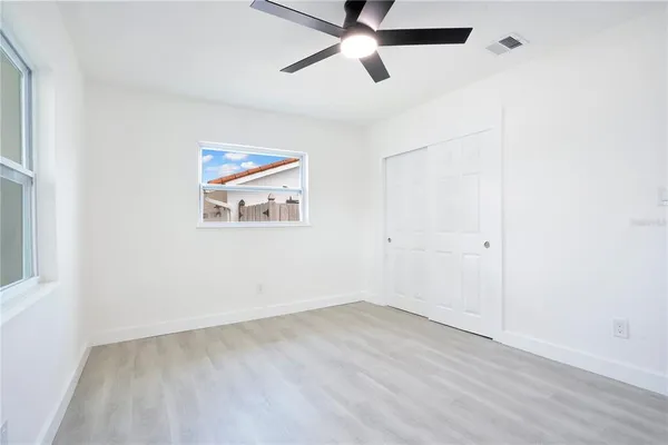 an empty room with a ceiling fan and window