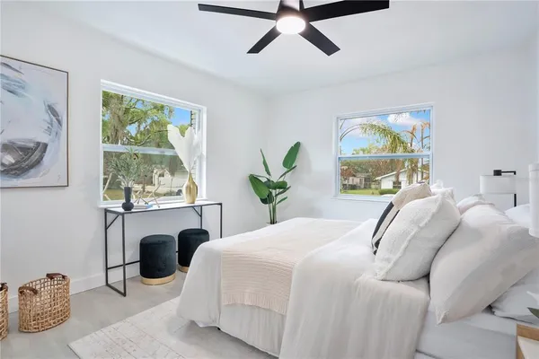a bedroom with a bed a computer on the desk and a window